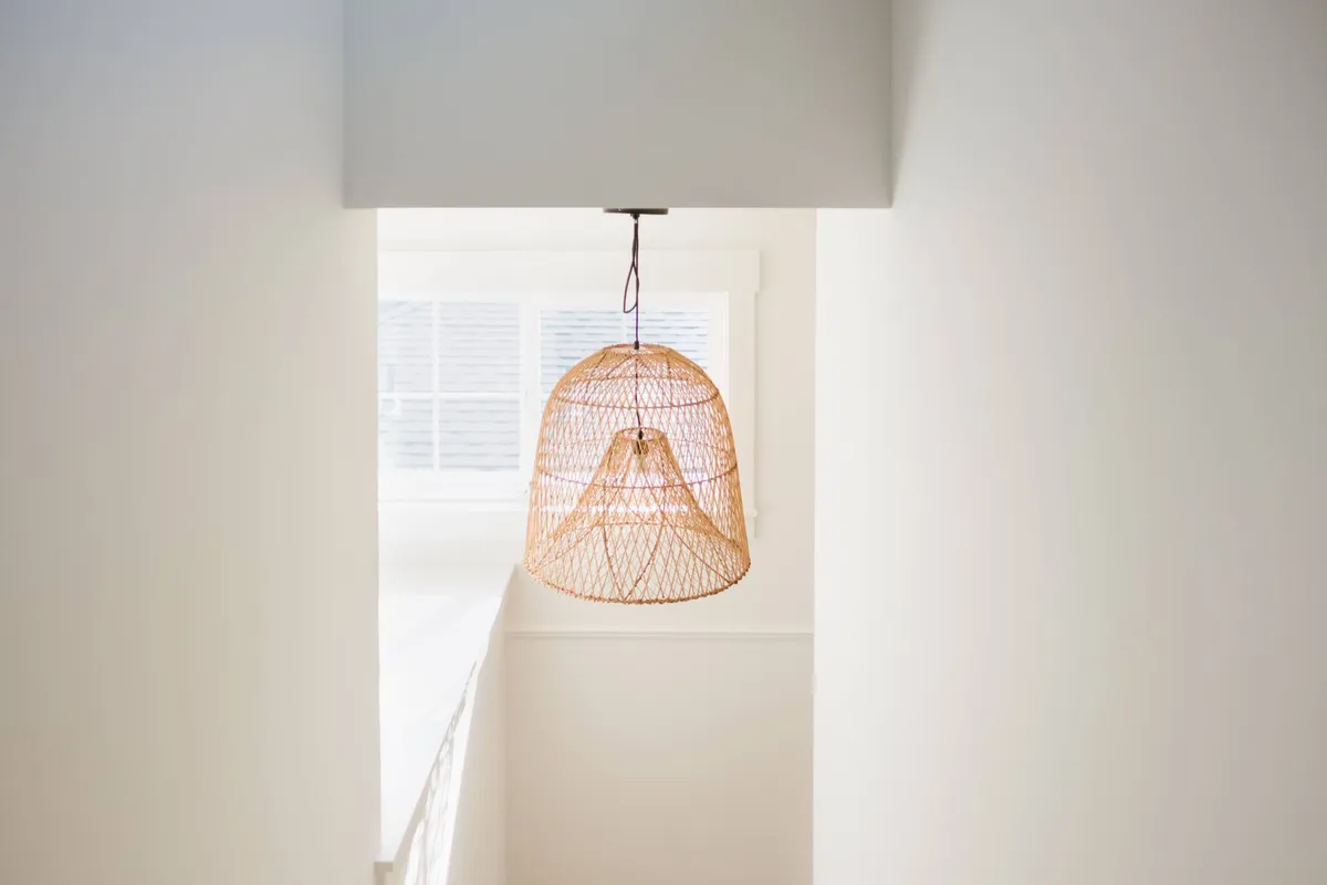 A peaceful nook with a woven pendant light and a sun-drenched window. The area looks ideal for relaxing with a book or planning the day's adventures in a quiet moment before or after exploring downtown.