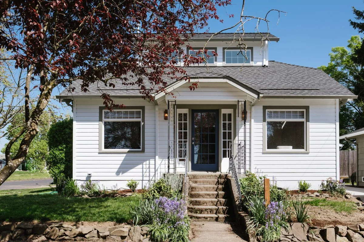 This image captures the bungalow’s welcoming front entrance, featuring a charming front door, steps leading up to the porch, and thoughtfully landscaped gardens. The inviting exterior radiates warmth, suggesting a peaceful retreat just steps away from the bustle of town.